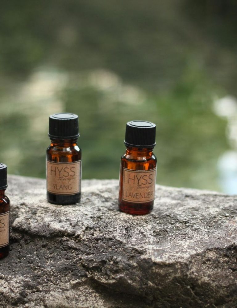 Tre små bruna glasflaskor med eteriska oljor på en stenmur.